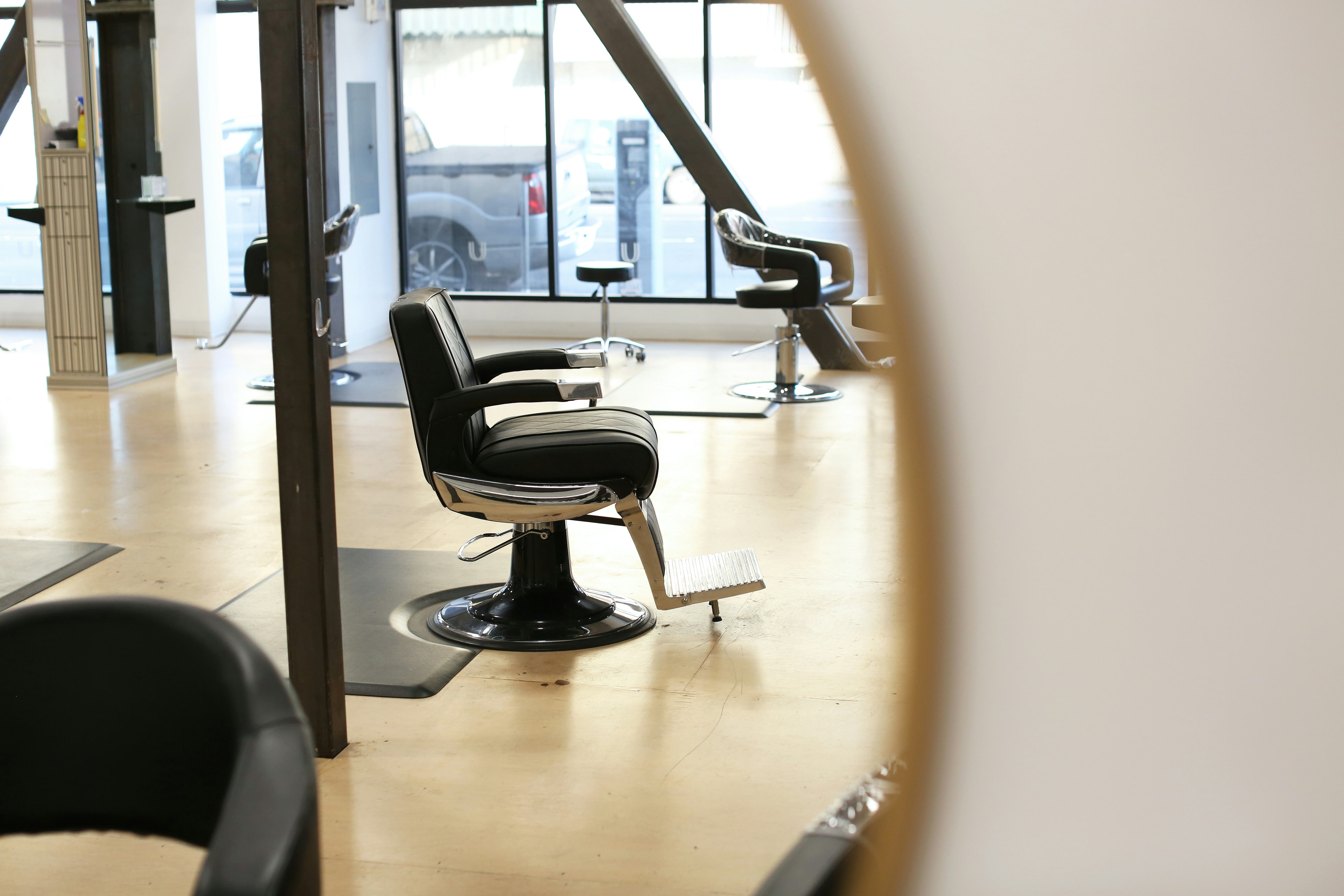 Fauteuil de salon vide devant un miroir, dans un salon de coiffure lumineux, symbolisant un rendez-vous manqué.